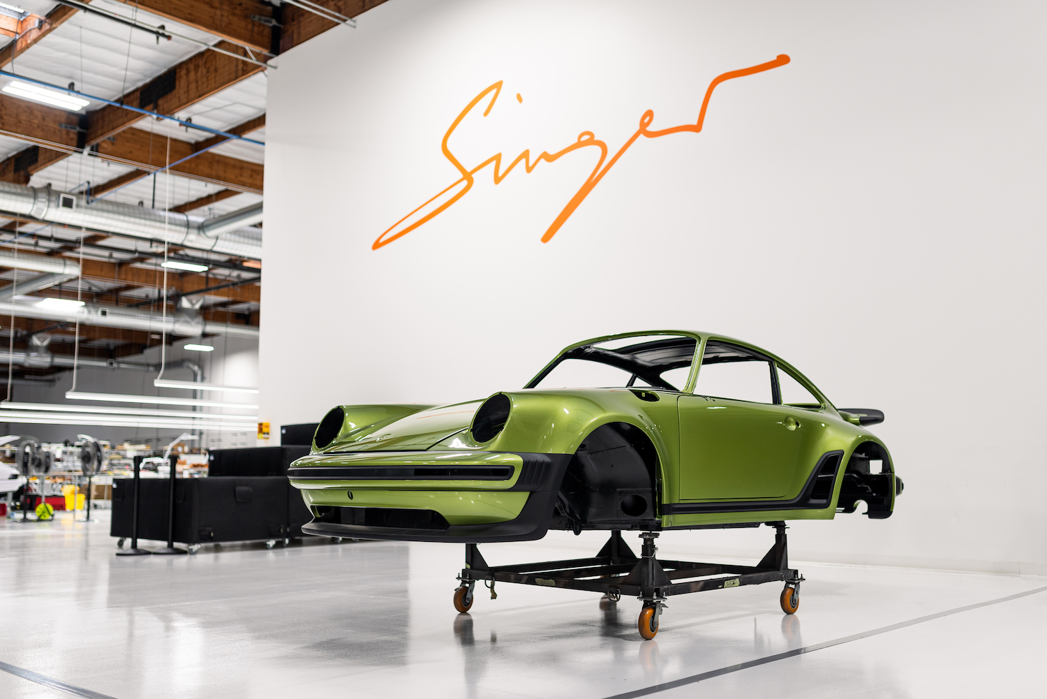 lime green car body on rolling wheels under "singer" sign