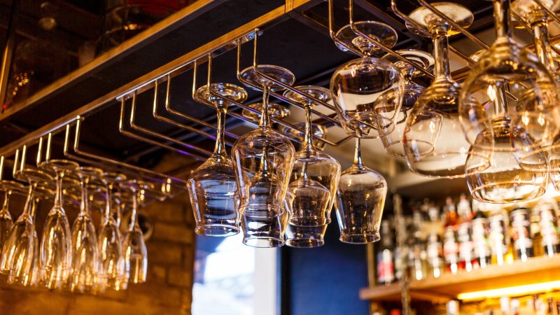 Empty drink glasses hanging from bar rack