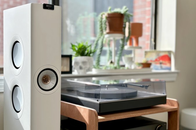  White KEF LS60 Wireless floorstanding speaker in front of a Cambridge Audio Alva TT V2 turntable and some plants