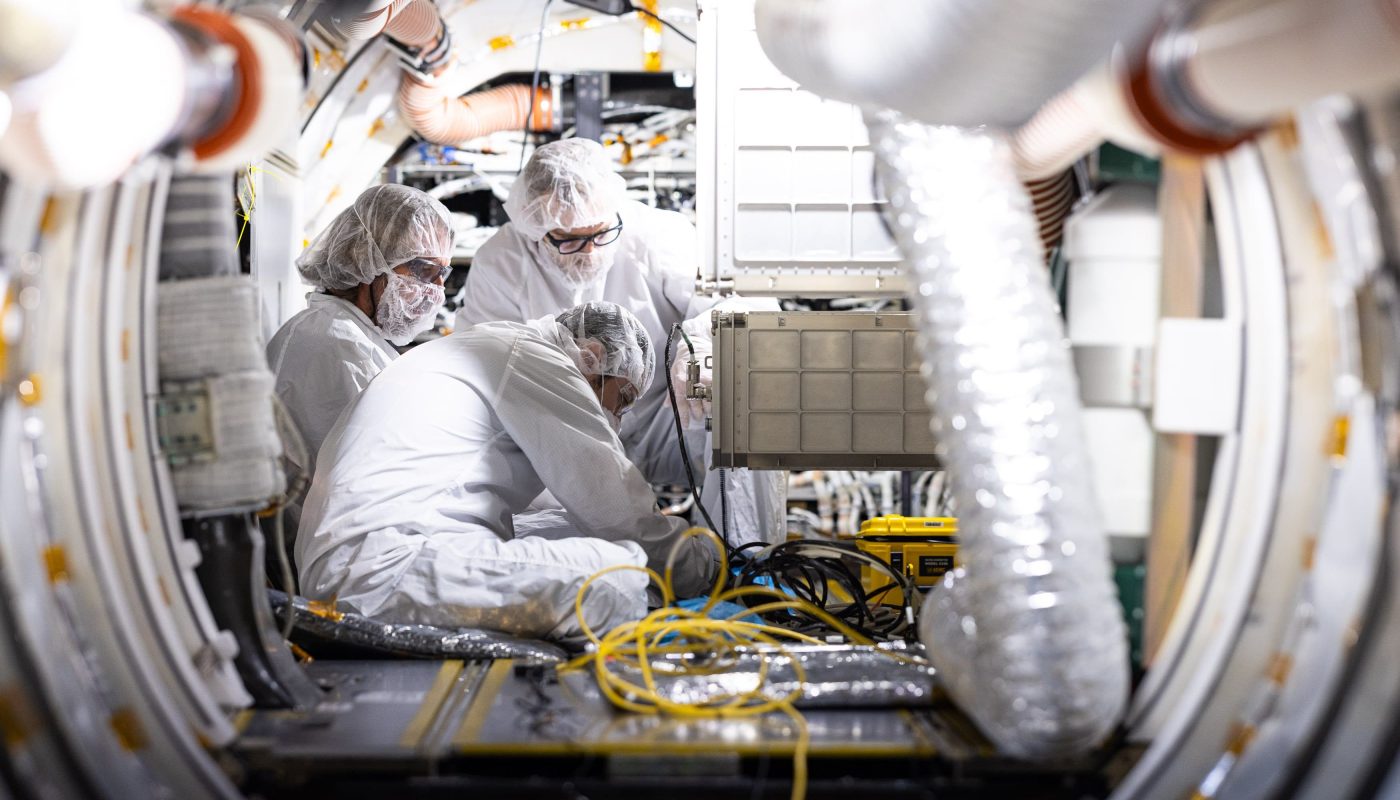 Three engineers testing material in Dream Chaser spaceplane cargo space