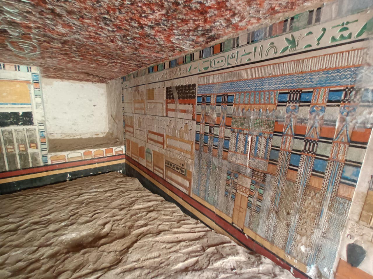 a colorful wall next to the sandy floor of an ancient egyptian tomb