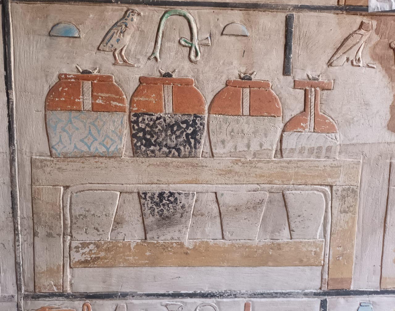 a line of hieroglyphics above an etching of four long vessels