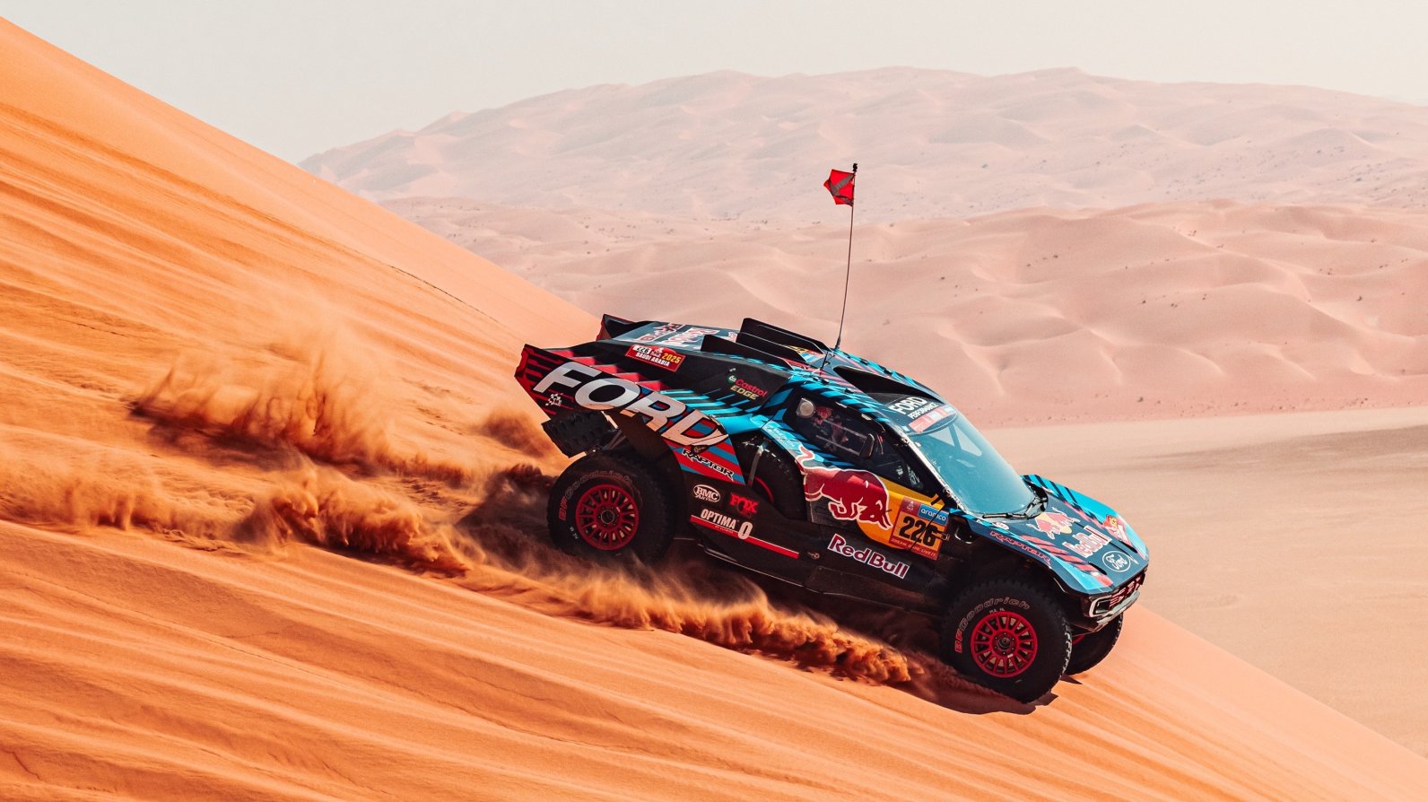 a beefed-up truck drives across desert dunes