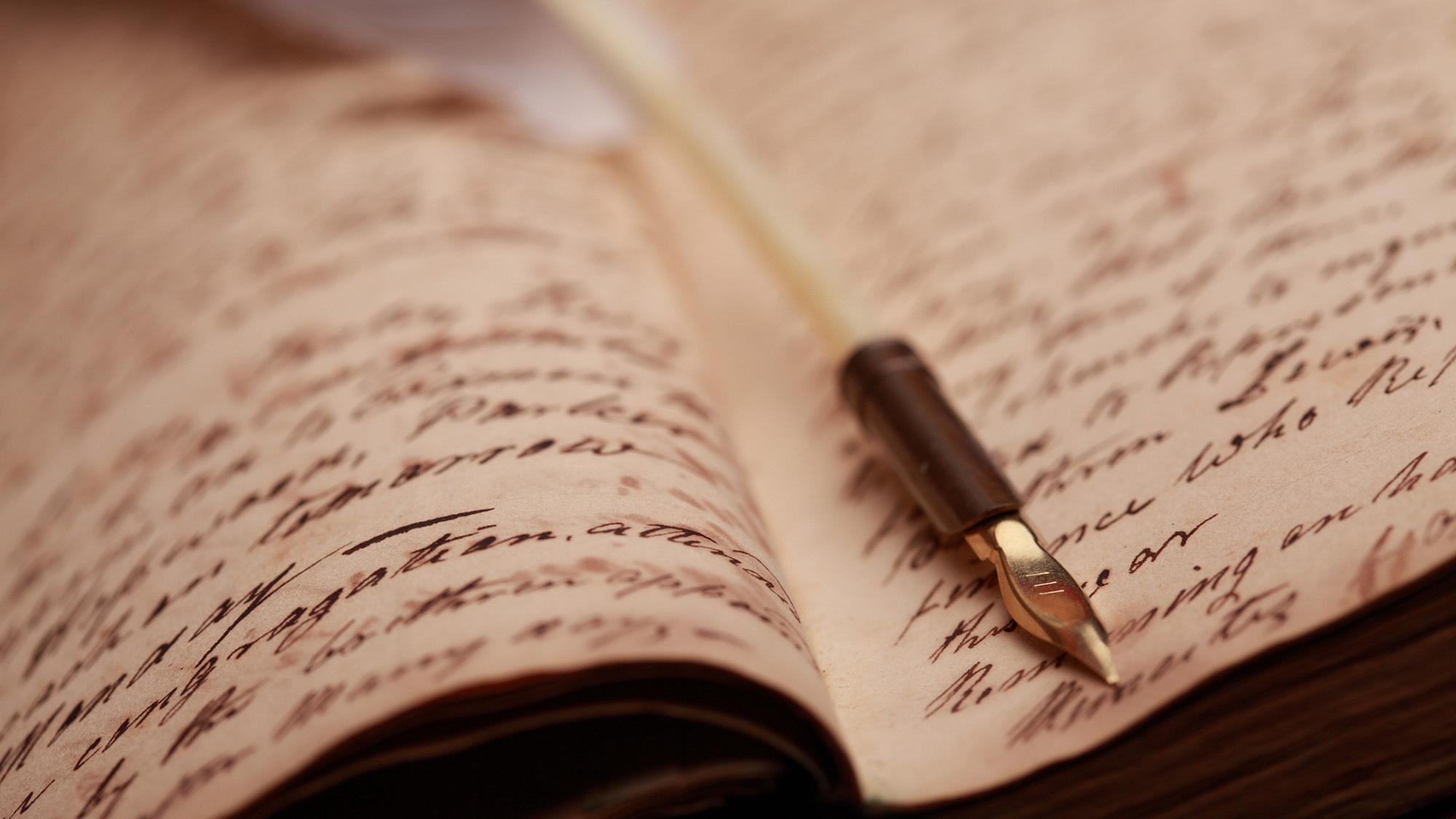 Quill pen on old journal with parchment background and handwriting.