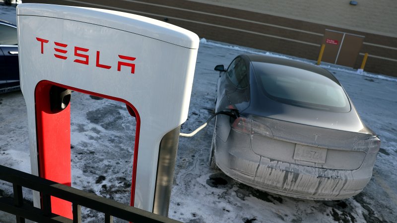 A Tesla charges in a salt and ice covered parking lot in Chicago on Jan. 17, 2024.