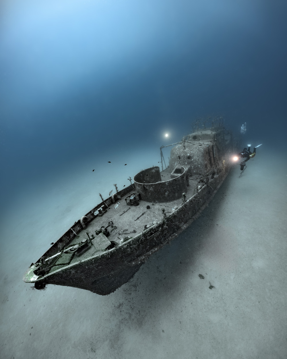 a shipwreck on the sea floor with a diver exploring