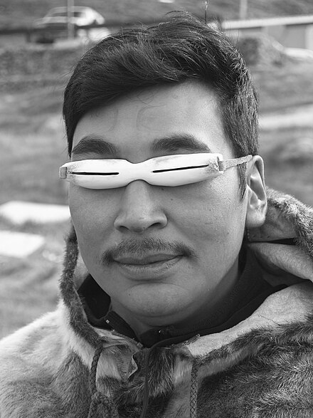 an inuit man wears sunglasses made from animal bones