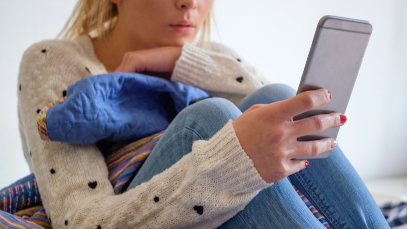 Girl using phone seated on the bed