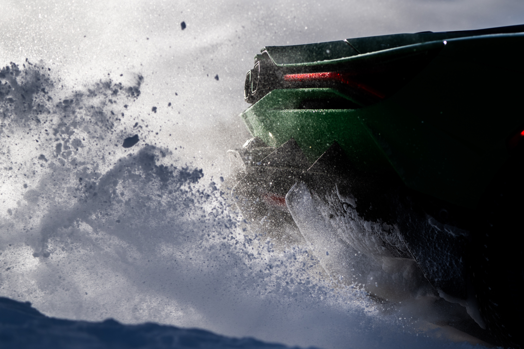 close-up of back part of sports car, kicking up snow and ice