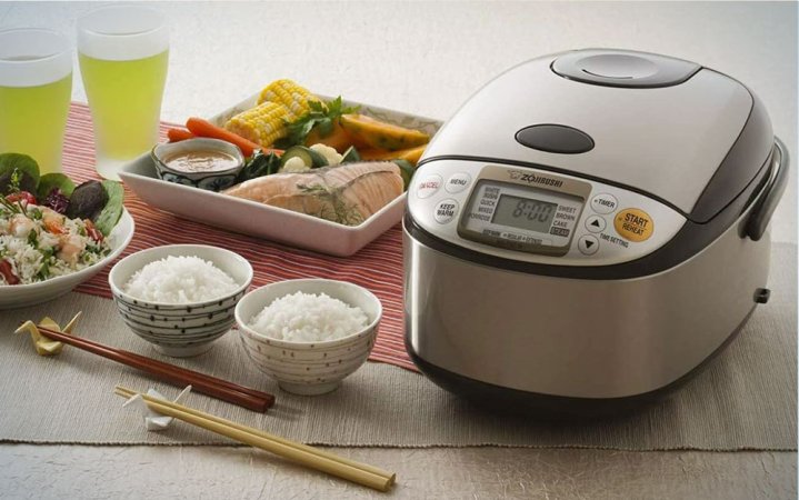  A Zojirushi rice cooker on a table with prepared food including rice