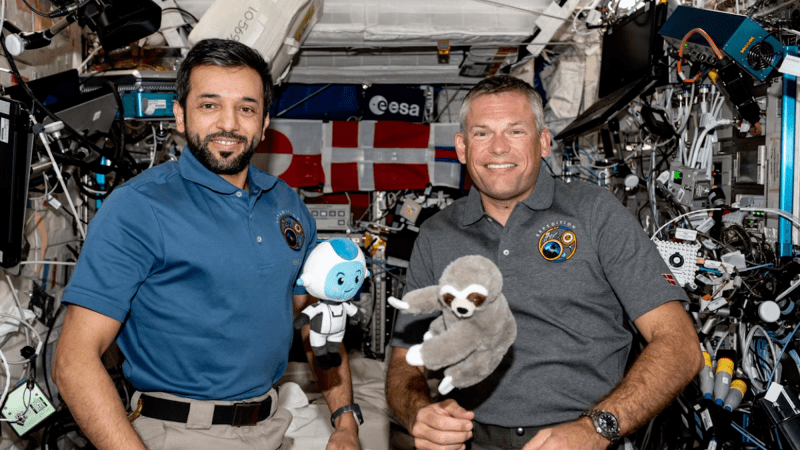 Two astronauts holding plushies inside ISS