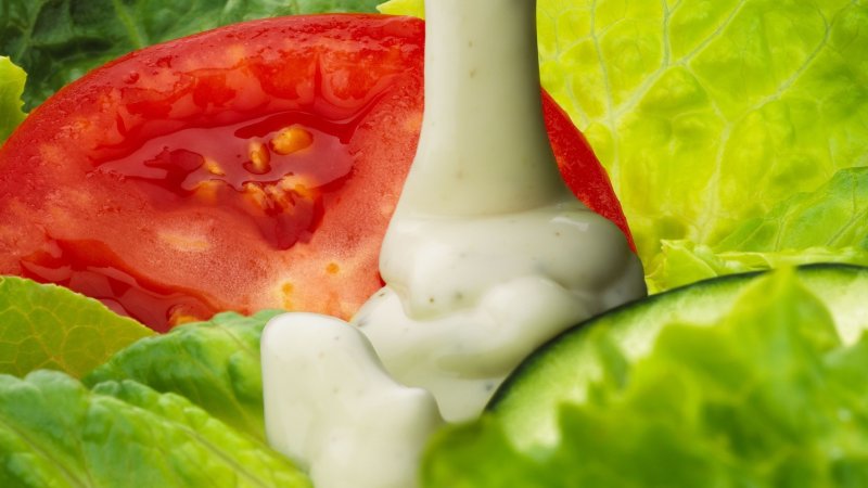 ranch dressing closeup. being poured on a tomato and lettuce